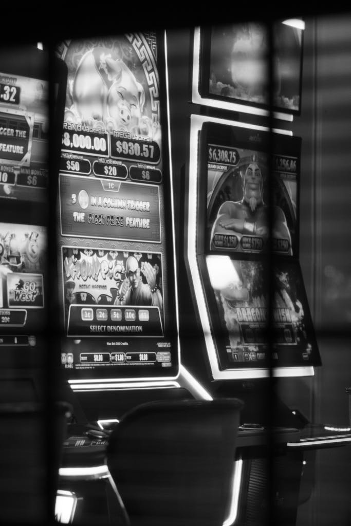 Monochrome image of casino slot machines reflecting lights.