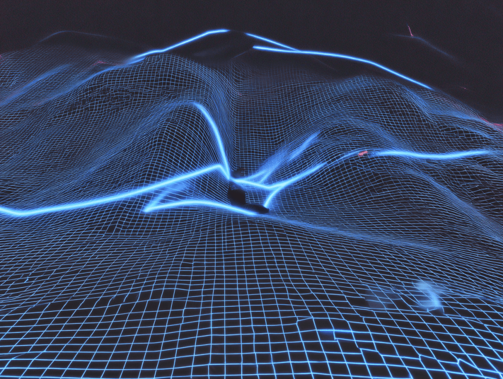 A digital landscape featuring a glowing blue grid forming 3D wave-like shapes across a dark background, resembling a stylized terrain or neural network visualization.