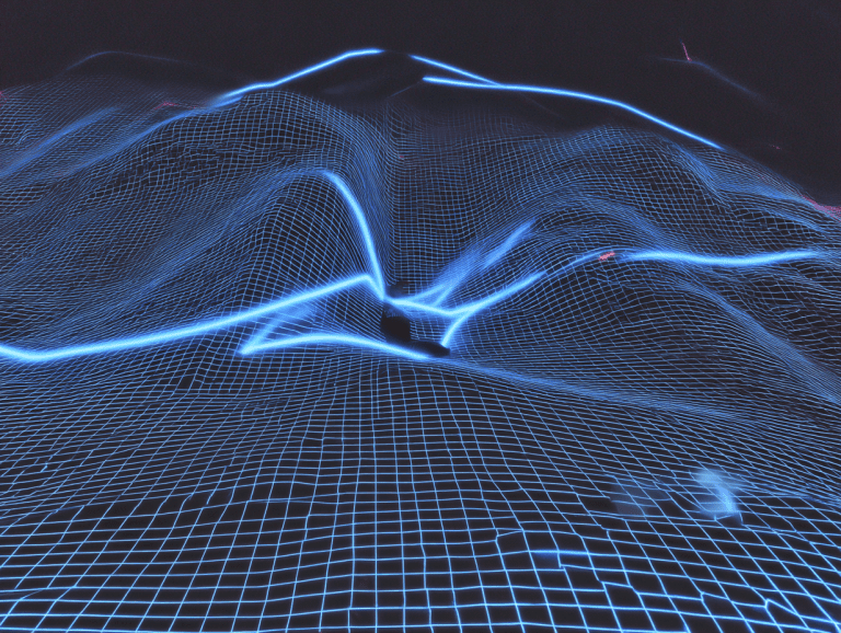 A digital landscape featuring a glowing blue grid forming 3D wave-like shapes across a dark background, resembling a stylized terrain or neural network visualization.